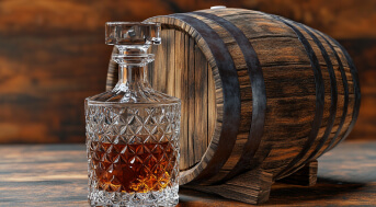 Mit Whisky befüllte Karaffe vor einem Holzfass